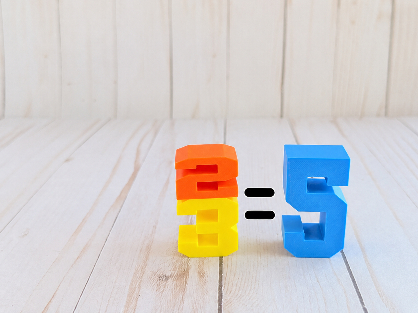 Numbini Zahlenbausteine zeigen spielerisch die Rechenaufgabe 2 plus 3 gleich 5 und unterstützen das Verständnis erster Additionen.